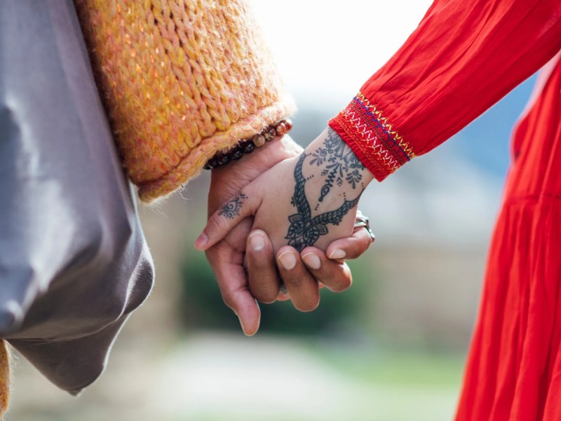 Zwei Personen halten Händchen, eine davon hat ein Boho Tattoo auf dem Handrücken