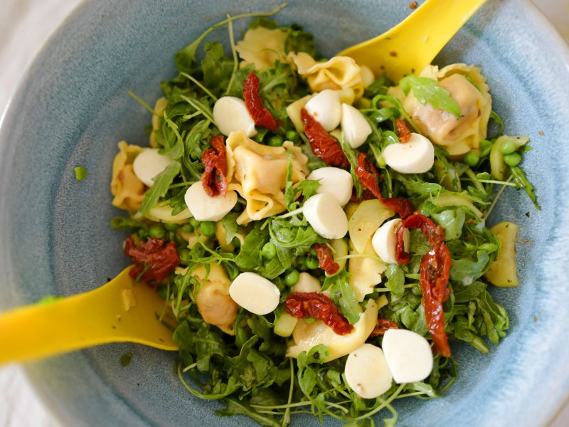 Schneller Salat zum Grillen: Tortellini Salat in blauer Sch&uuml;ssel mit gelbem Salatbesteck