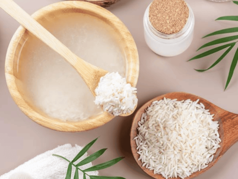 Hausgemachtes kosmetisches Reiswasser mit Zutaten und Beauty-Set auf beigefarbenem Hintergrund