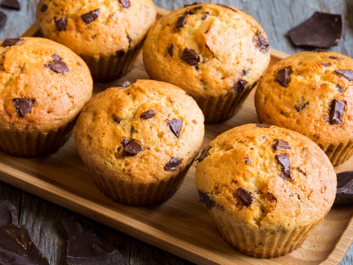 Muffins mit Schokost&uuml;ckchen auf einem Holzbrett.
