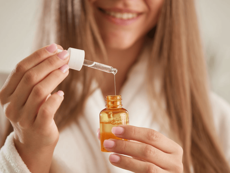 Frau mit langem Haar hält Serum in den Händen