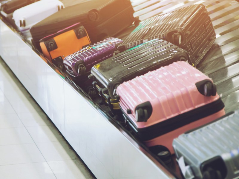Bunte Koffer auf einem Gep&auml;ckband am Flughafen.