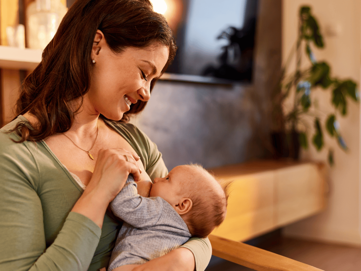 Junge Frau h&auml;lt ihr Baby vor sich und stillt es