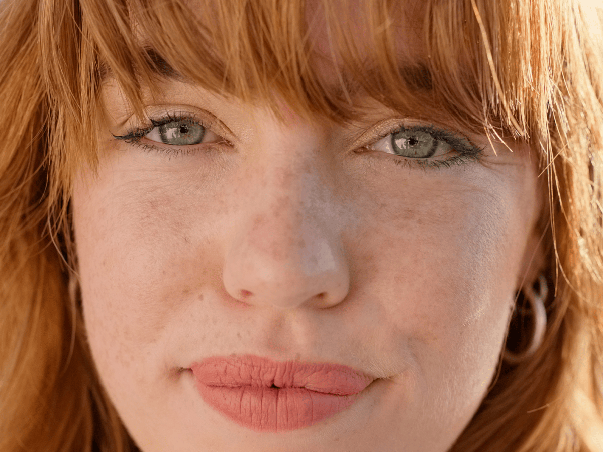 Frau mit roten Haaren, heller Haut und Sommersprossen