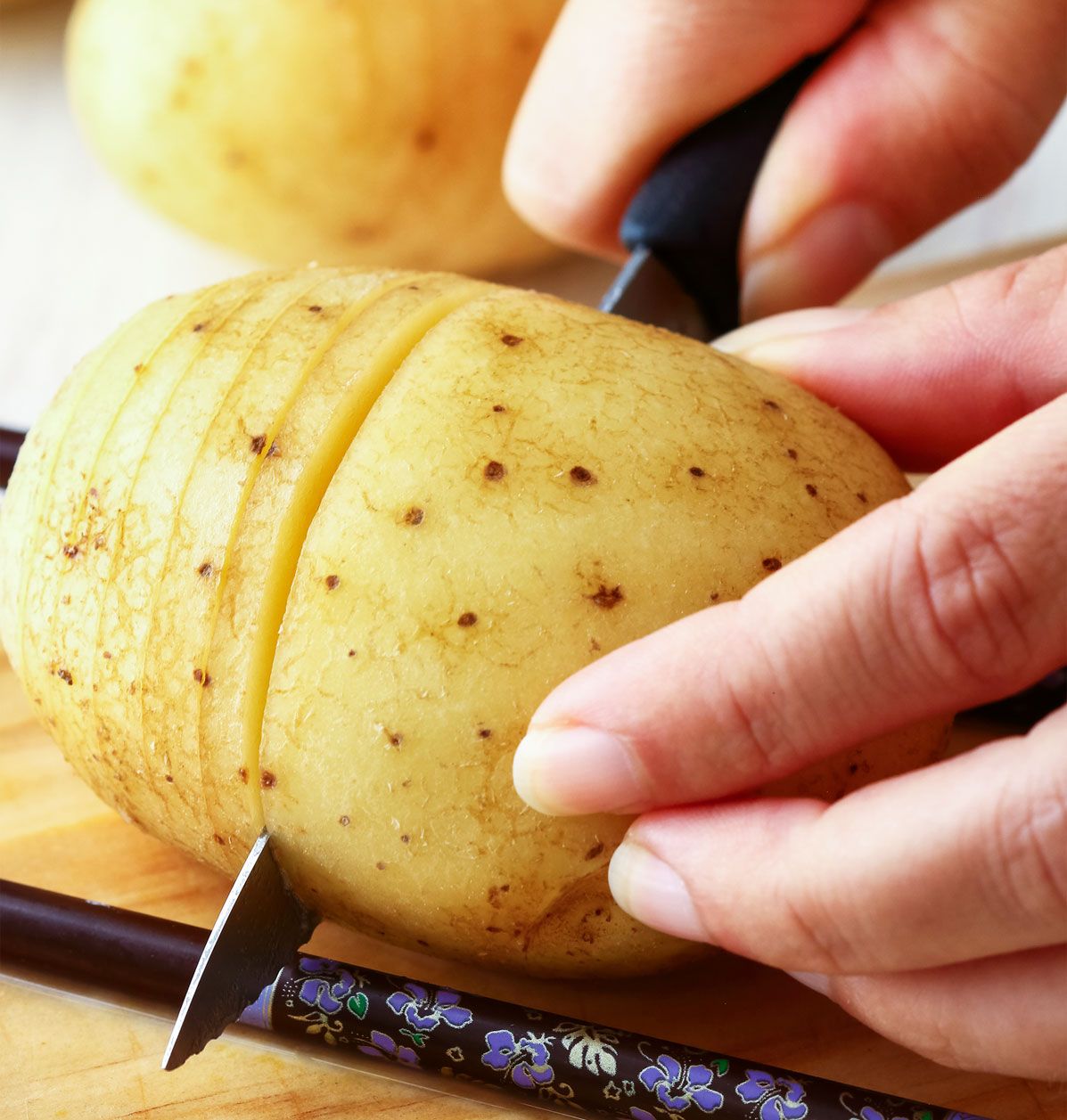 Mithilfe von Essstäbchen lassen sich Hasselback-Kartoffeln einfach schneiden Mithilfe von Essstäbchen lassen sich Hasselback-Kartoffeln einfach schneiden