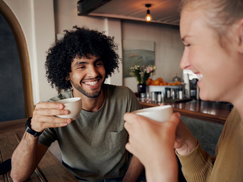 Mann und Frau beim Kaffeetrinken, die sich gegenseitig anl&auml;cheln