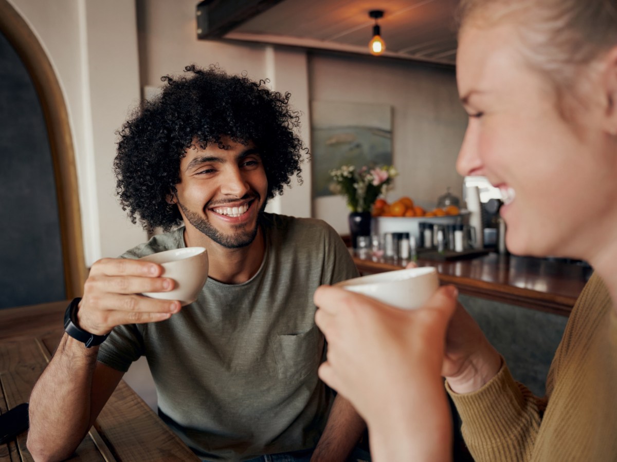 Mann und Frau beim Kaffeetrinken, die sich gegenseitig anl&auml;cheln