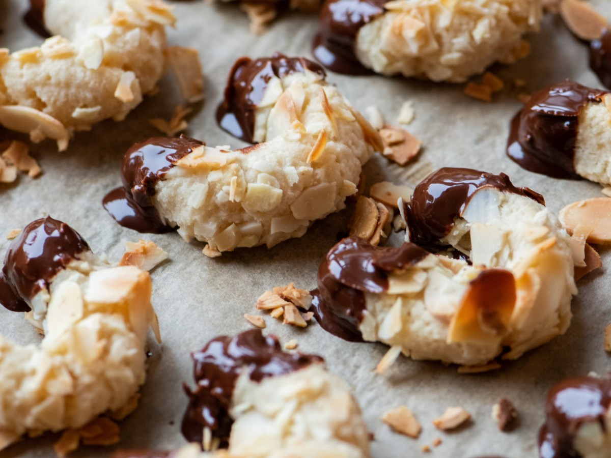 Mandelh&ouml;rnchen mit Schokoenden auf einem Backblech.