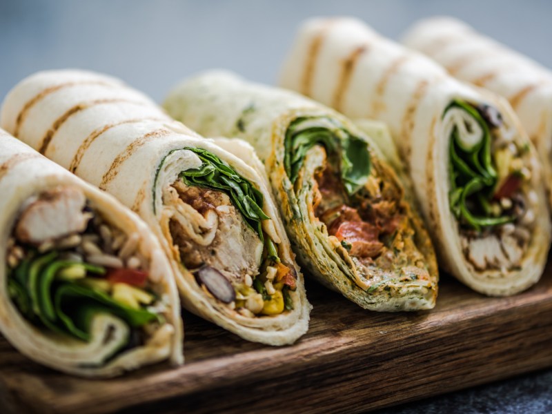 Gef&uuml;llte Wraps auf einem Holzbrett.