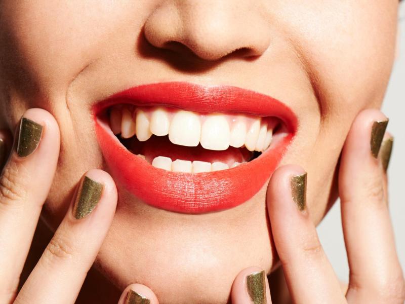 Frau mit Lippenstift lacht und hat ein strahlendes wei&szlig;es L&auml;cheln.