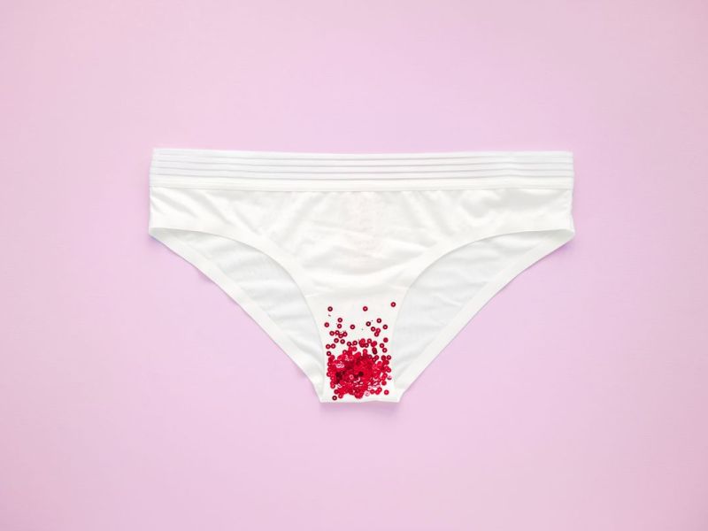 Bild eines wei&szlig;en Slips vor einem rosa Hintergrund mit roten Flecken, die an Blutflecken erinnern.