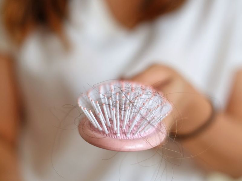 Eine Frau h&auml;lt eine Haarb&uuml;rste in der Hand
