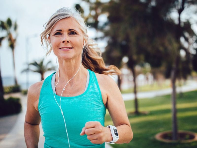 Frau mittleren Alters ist draußen joggen.