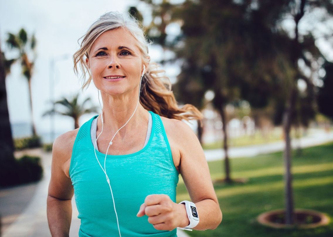 Frau mittleren Alters ist draußen joggen.