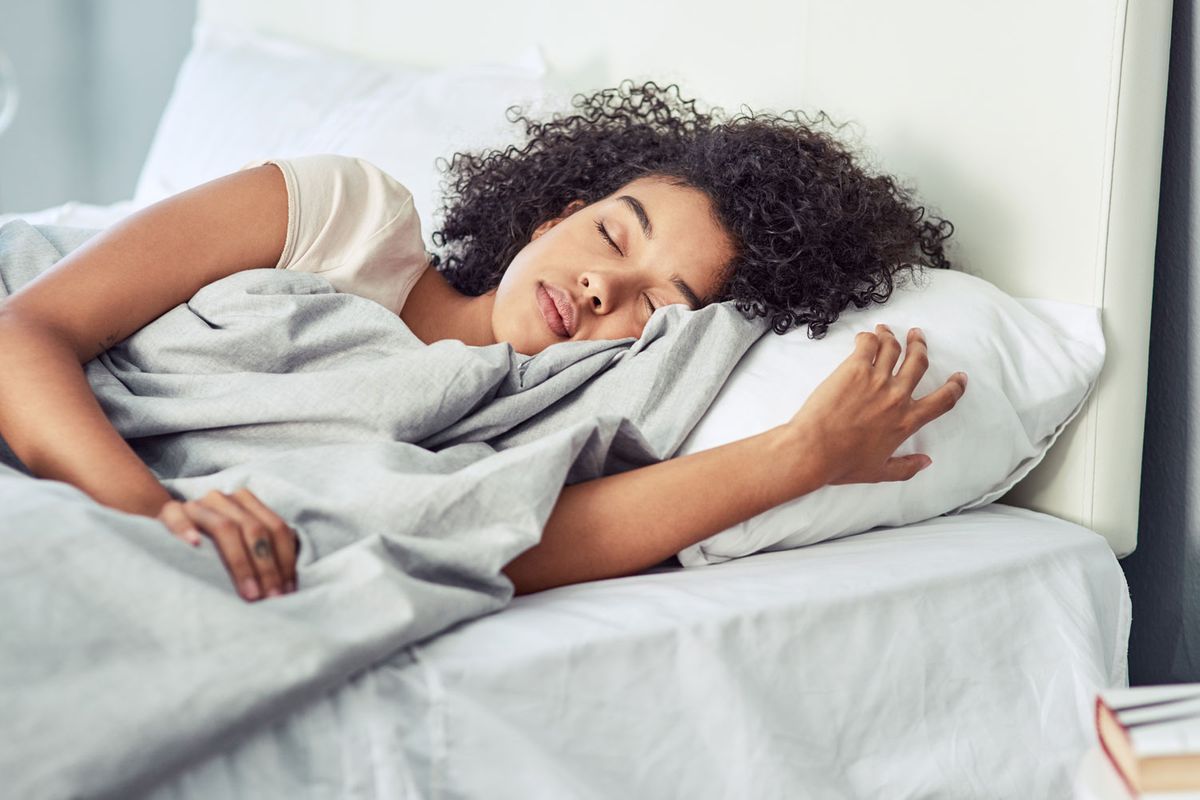 Frau liegt auf dem Bett auf einer Seite und schl&auml;ft.