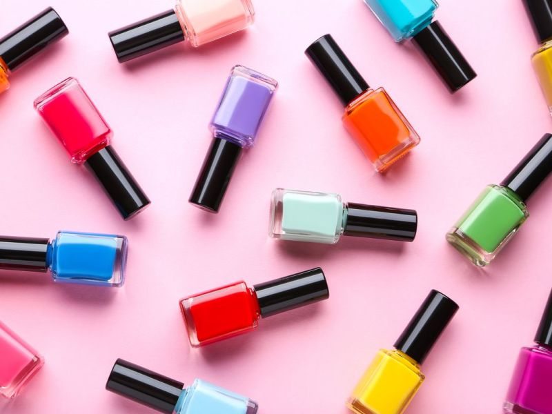 Bunte Nagellackflaschen vor einem rosa Hintergrund