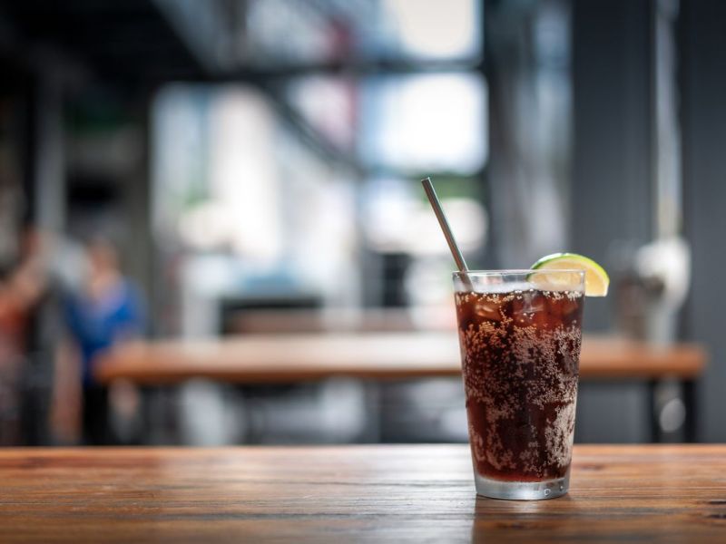 Ein Glas Cola mit Zitrone steht in einem Restaurant auf dem Tisch.