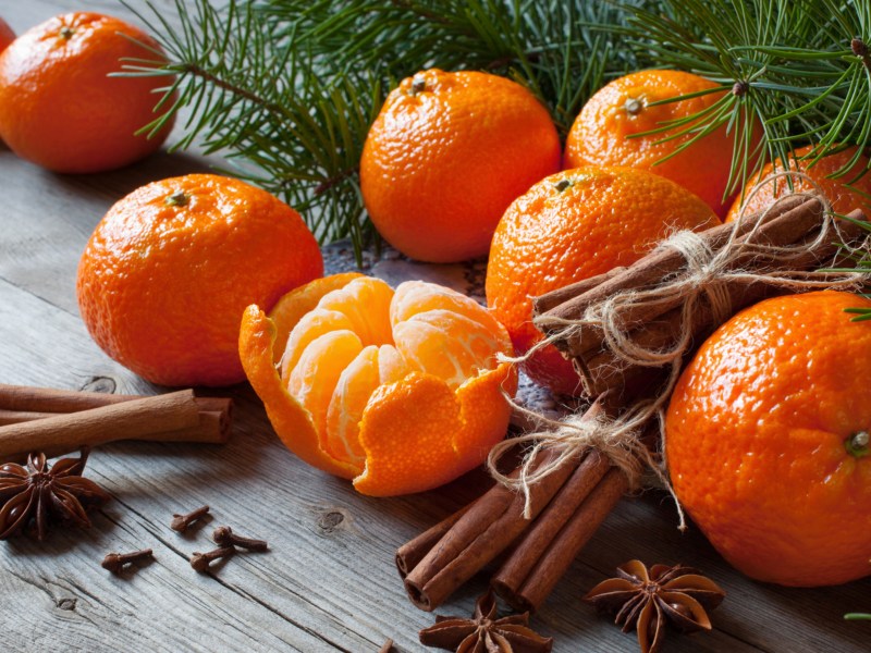 Mandarinen neben Tannengr&uuml;n und Zimtstangen.