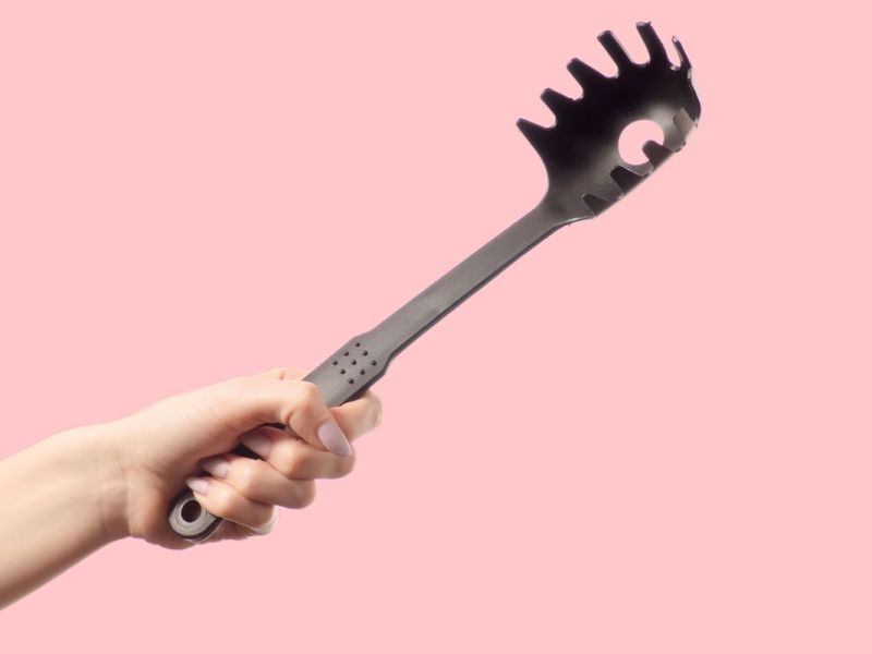 Hand mit schwarzem Spaghetti Löffel