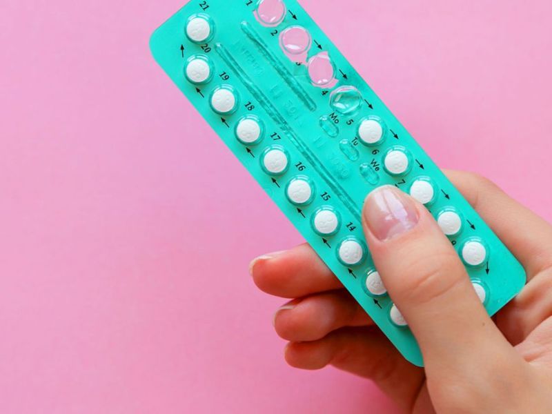 Weibliche hand hält Pillenblister vor pinkem Hintergrund