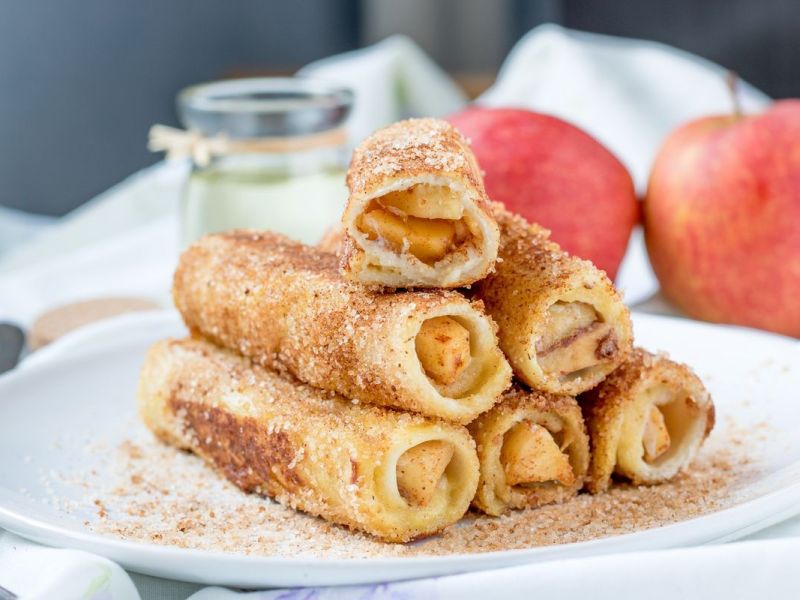 Apfel-Toast-R&ouml;llchen auf einem wei&szlig;en Teller.