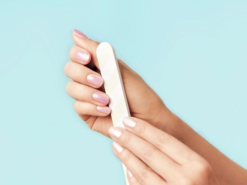 Fingernägel werden mit einer Nagelfeile in Form gebracht
