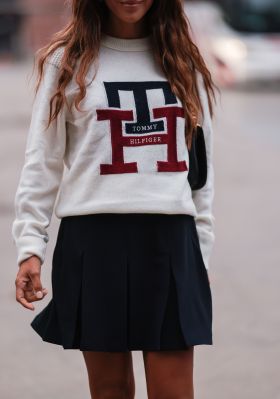 Kombi im College-Stil: Tennisrock und Strickpullover mit Emblem. Kombi im College-Stil: Tennisrock und Strickpullover mit Emblem.