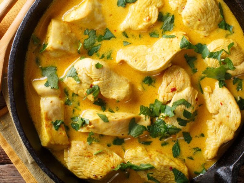H&auml;hnchen mit Curryso&szlig;e in einer gro&szlig;en Pfanne.