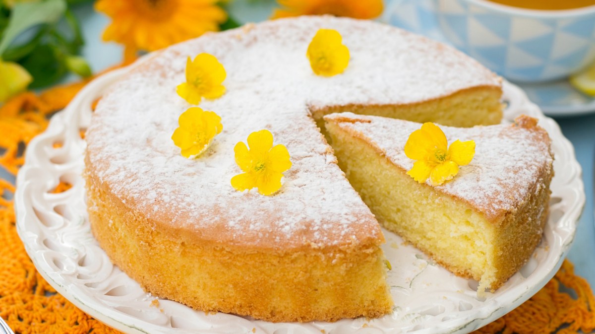 Luftiger Zitronenkuchen auf weißem Kuchenteller.