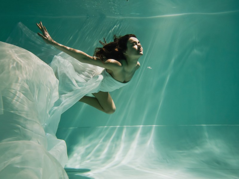 Frau schwimmt in wei&szlig;em Kleid.