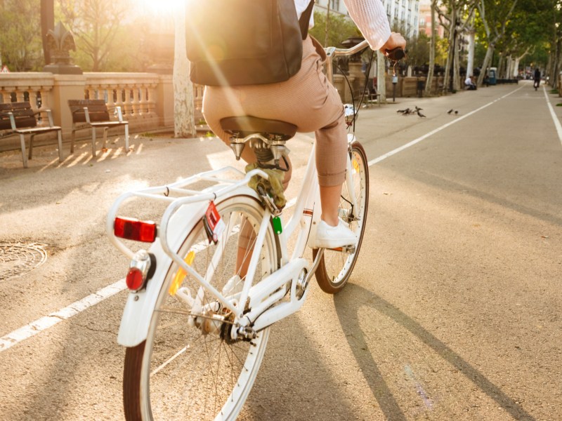 Mann auf einem Fahrrad, der im Sonnenlicht auf einem Fahrradweg f&auml;hrt