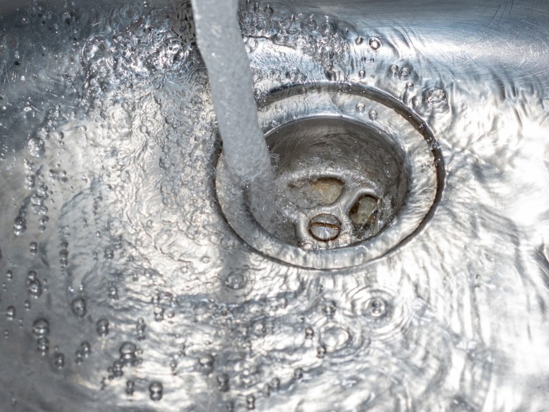 Wasser l&auml;uft einen Abfluss herunter.