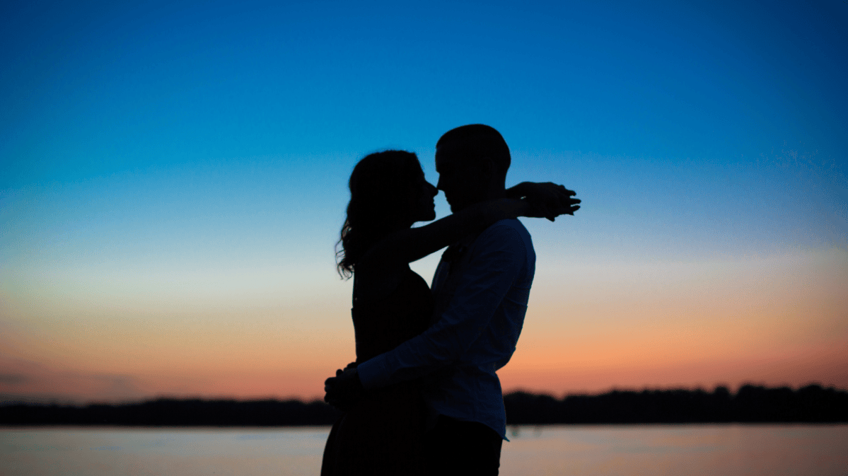 Die Silhouette eines Pärchens beim Sonnenuntergang.