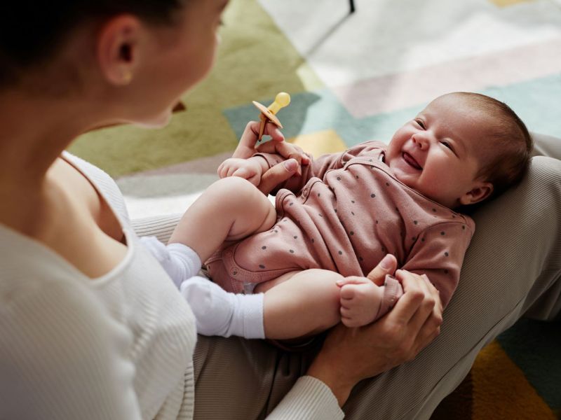 Lachendes Baby auf dem Scho&szlig; der Mutter