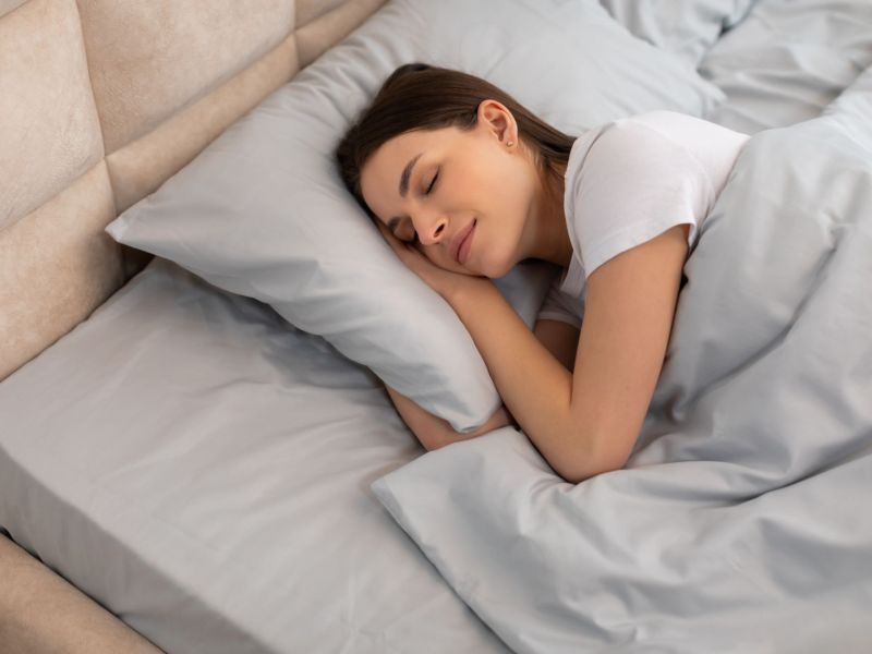 Dunkelhaarige Frau schlafend mit Decke im Bett als Symbolbild für "Gewichtsdecken-Test"