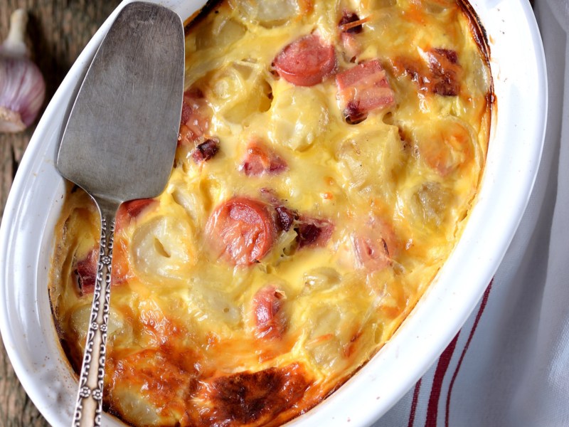 Kartoffelgratin mit W&uuml;rstchen in wei&szlig;er Auflaufform.