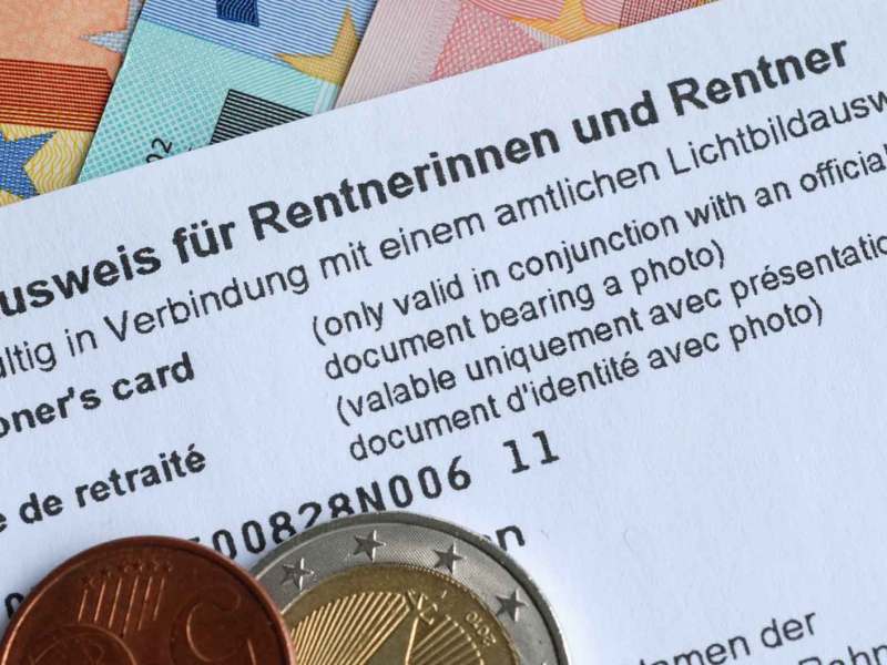 Ein Rentenausweis liegt auf Geldscheinen. Darauf liegen Geldm&uuml;nzen.