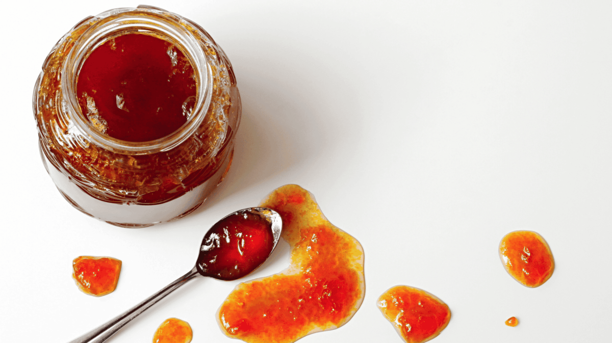 Offenes Marmeladenglas und Marmelade auf einem Löffel