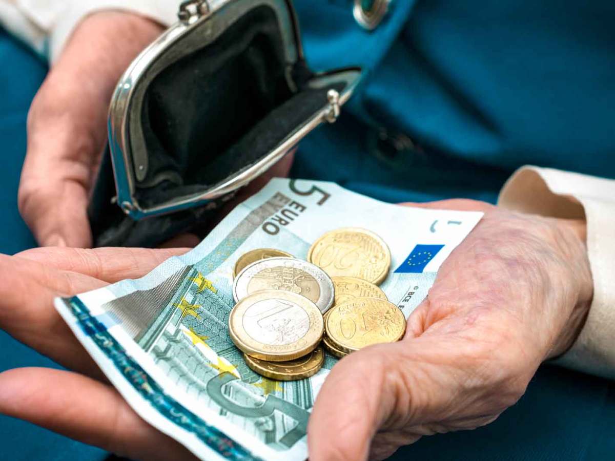 &Auml;ltere Frau hat Geld aus ihrer Geldb&ouml;rse genommen und h&auml;lt Scheine und M&uuml;nzgeld in der Hand.