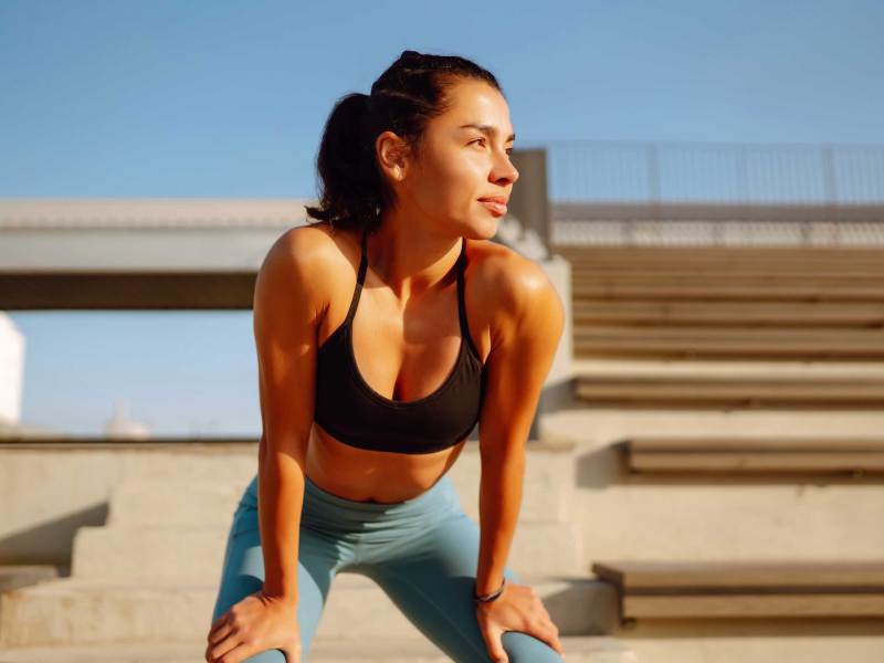 Junge, sportliche Frau beim Training und Stretching im Freien am Morgen.