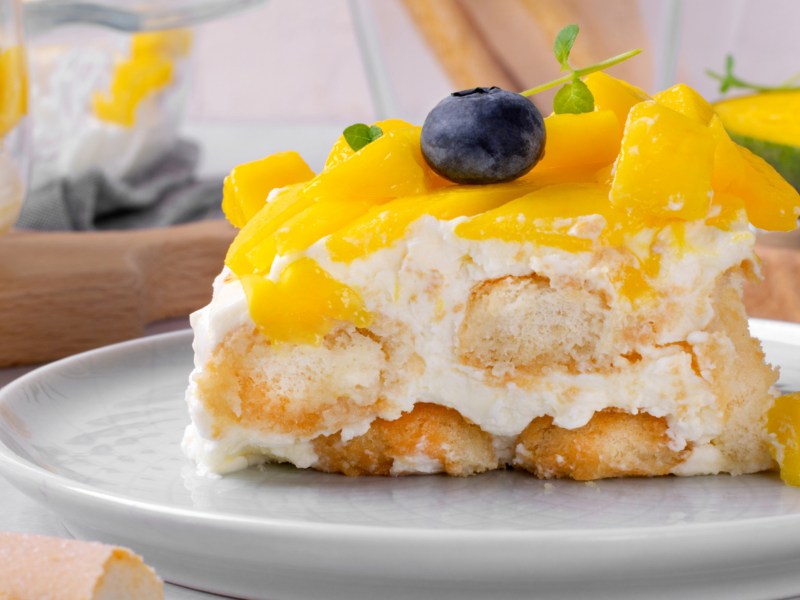 Tiramisu mit Mango-Sauce auf einem wei&szlig;en Teller.