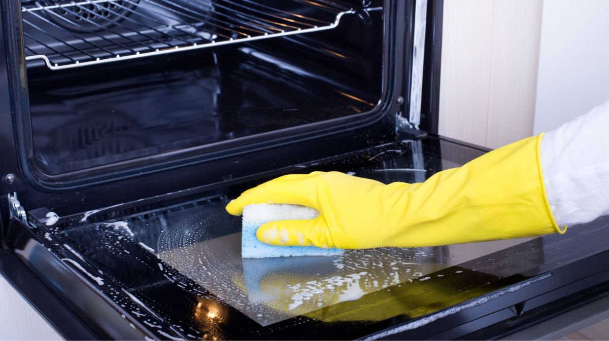 Person reinigt Backofen mit einem Schwamm