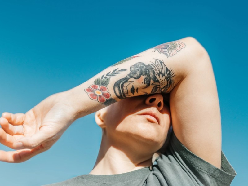 Frau mit Tattoos vor einem blauen Himmel