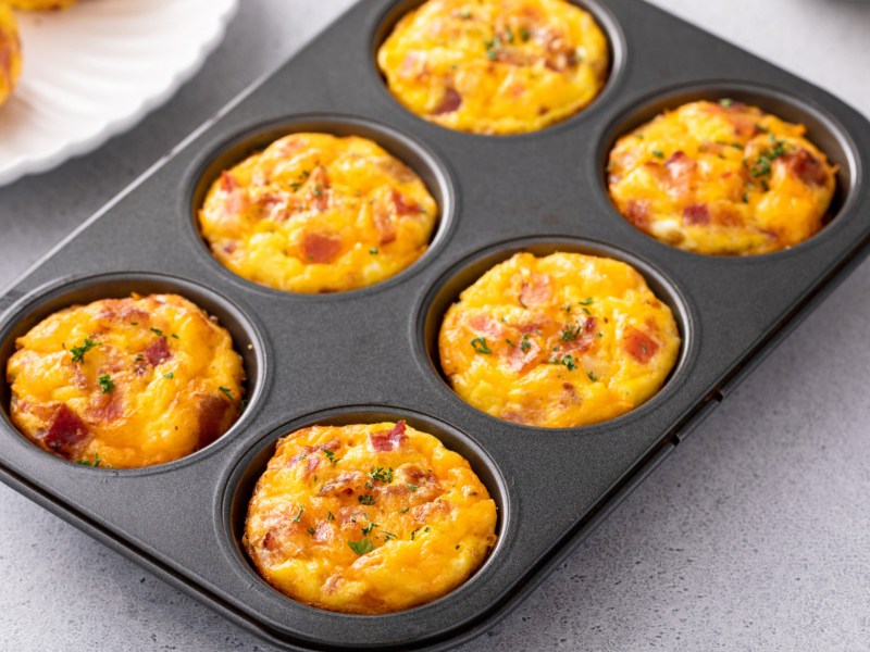 Eiermuffins in einem 6-Muffinblech auf einem Esstisch.