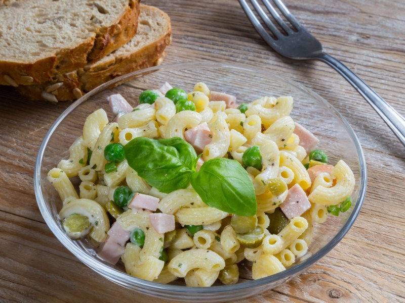 Nudelsalat in Glassch&uuml;ssel mit Fleischwurst, Erbsen und Gurken.