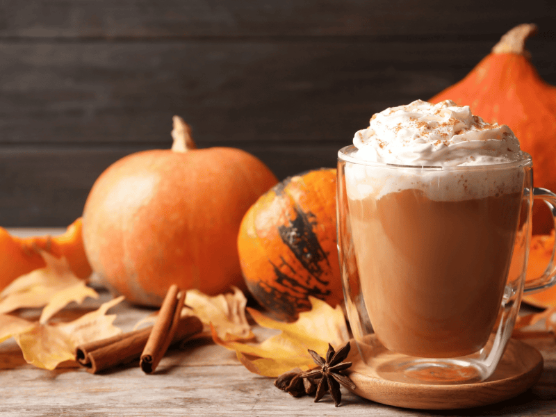 Glasbecher mit einem leckeren K&uuml;rbis-Gew&uuml;rz-Latte auf einem Holztisch&nbsp;