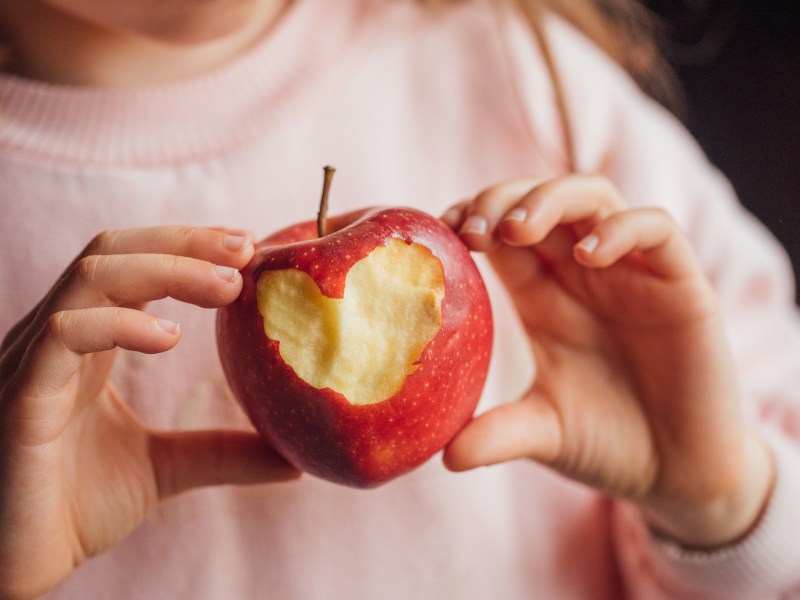 Hand mit Apfel, in dem Herz hineingebissen wurde