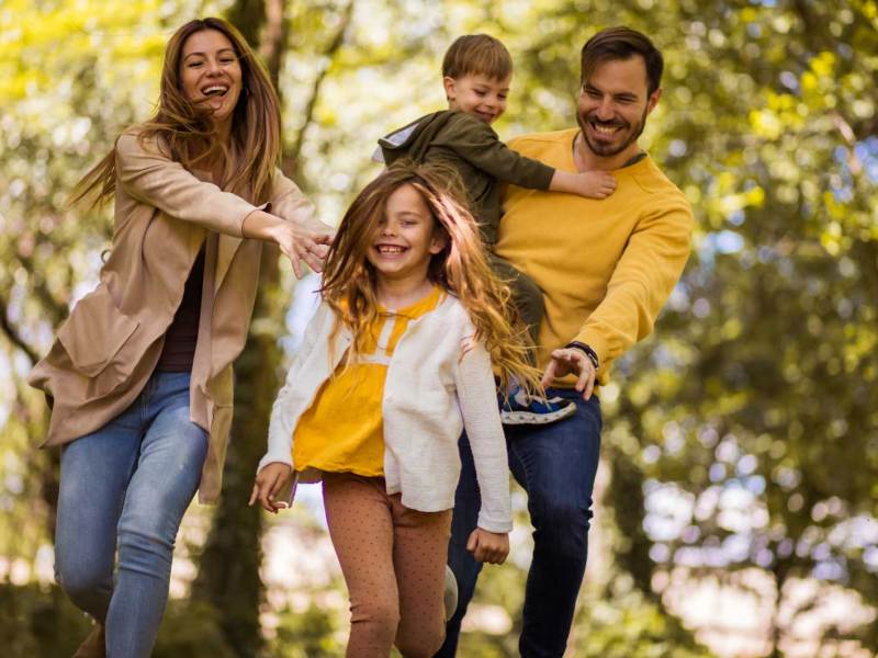 Vierk&ouml;pfige Familie hat Spa&szlig; bei einem herbstlichen Waldspaziergang.