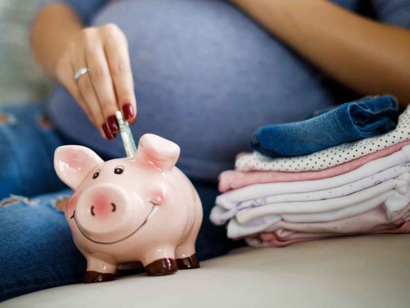 Schwangere Frau wirft Geldscheine in ein Sparschwein.