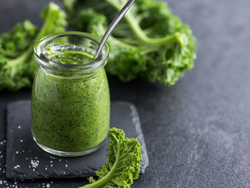Gr&uuml;nkohl Pesto in einem Glas auf grauem Untergrund